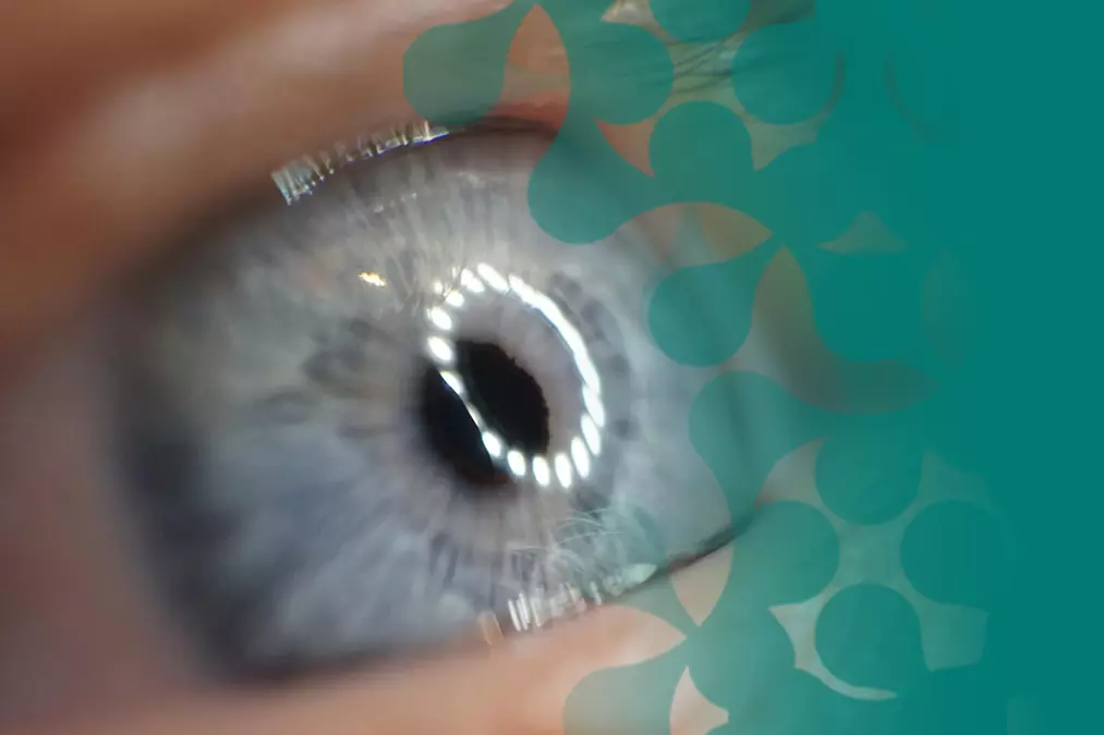A close-up image of an eye reflecting screens and data